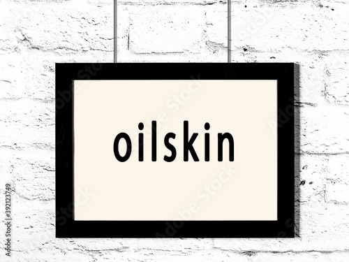 Black frame hanging on white brick wall with inscription oilskin