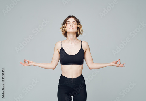 Woman in sportswear gestures with her hands on a gray background Copy Space