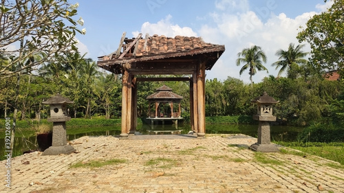 View of the gazebo through the arch. Lake, trees and Asian architecture. Tropical landscape in Ao Dai Museum. Ho Chi Minh City (Saigon). Vietnam. South-East Asia © Pavlo