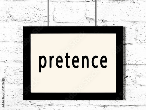 Black frame hanging on white brick wall with inscription pretence