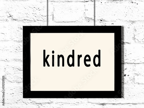 Black frame hanging on white brick wall with inscription kindred
