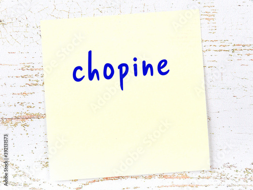 Yellow sticky note on wooden wall with handwritten word chopine photo