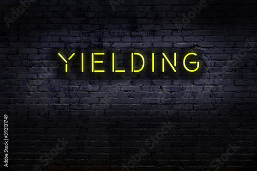 Schilderij op canvas Night view of neon sign on brick wall with inscription yielding