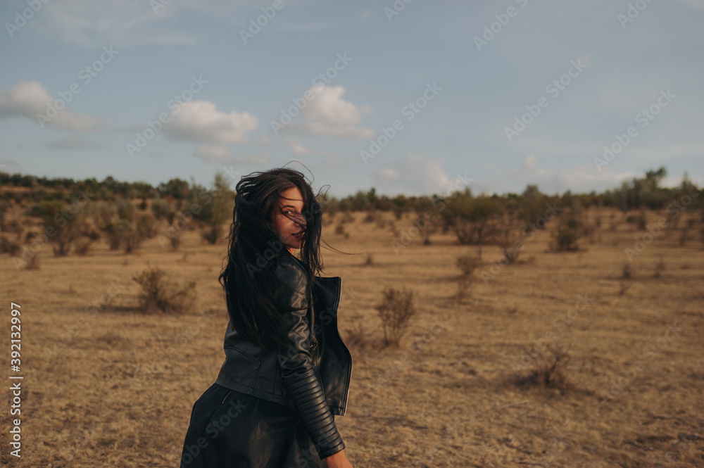 A photo session with a young lady dressed in black in nature, in the background is a brown chain