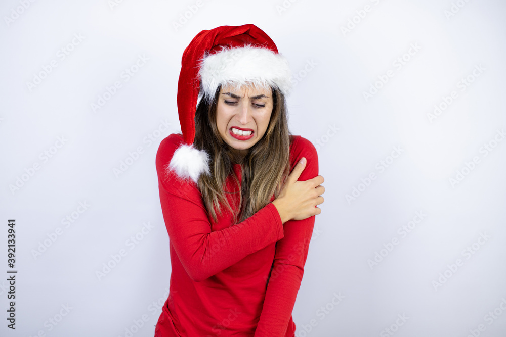 Young beautiful woman wearing a Santa hat over white background with pain on her shoulder and a painful expression