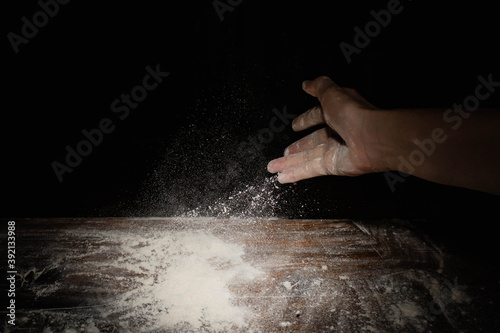 closeup of hand sprinkling flour on table with black background córdoba argentina