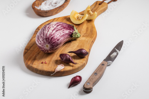 Canvas Print Closeup of nubia eggplant, garlic, and shallots on a small wooden cutting board