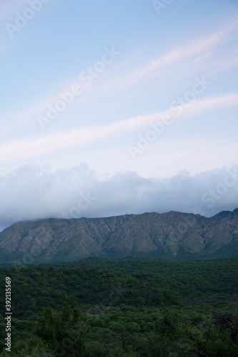 Enchanting view of popular landmark Uritorco hill, valley and green forest at sunset, in Capilla del Monte, Cordoba, Argentina.