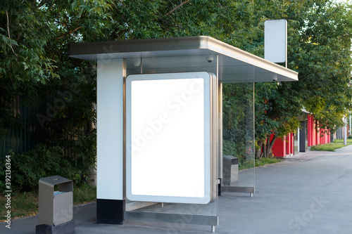 Fototapeta Naklejka Na Ścianę i Meble -  Vertical blank billboard at the bus station against the background of green tree crowns, mock-up.