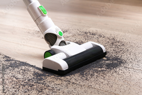 Photography A man uses a bagless vertical cordless vacuum cleaner to clean the floor