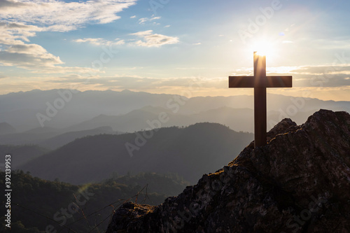 Silhouettes of crucifix symbol on top mountain with bright sunbeam on the colorful sky background