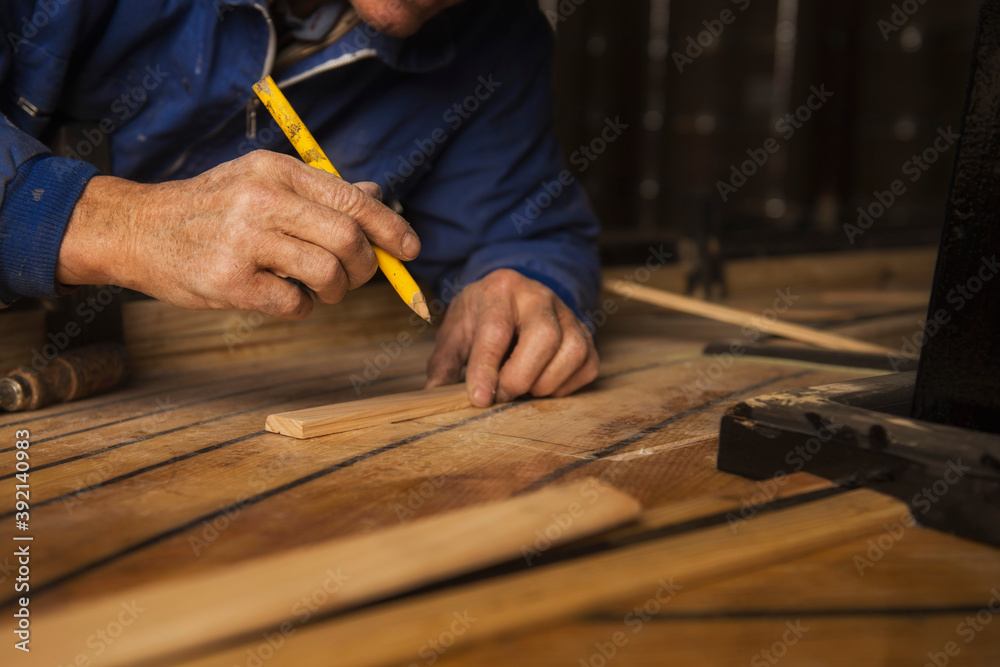 wood craftsman taking measurements for the construction of a traditional boat