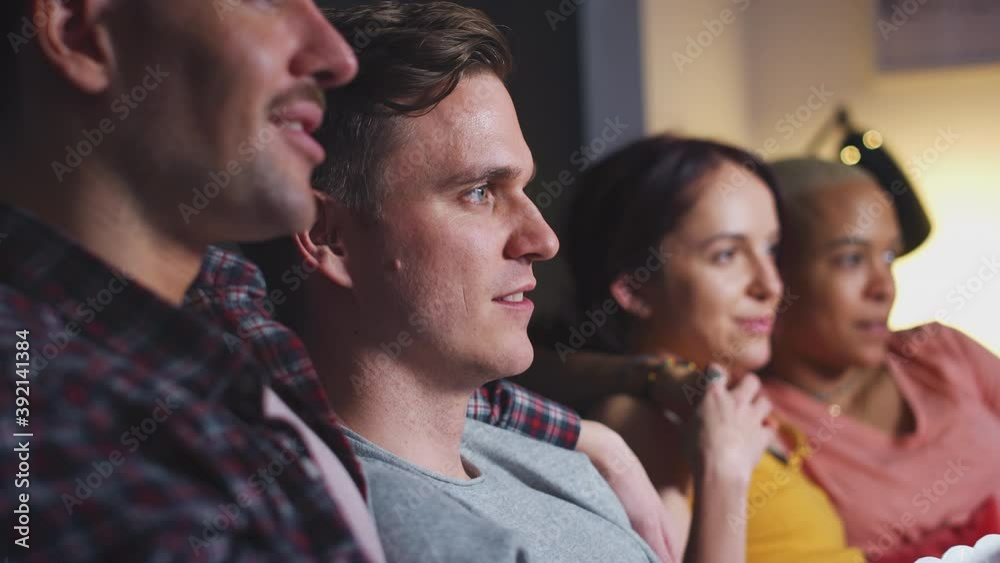 Group of gay friends sitting on sofa at home eating popcorn and laughing watching evening comedy TV together - shot in slow motion Group of gay friends sitting on sofa at home eating popcorn and laughing watching evening comedy TV together - shot in slow motion