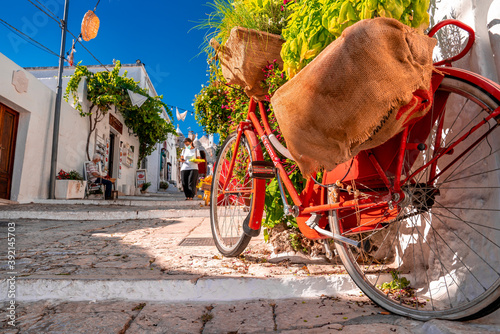 Classical bicycle parked in the middle of the old town surrounded with flowers and trafitional Greece, Italian style. photo