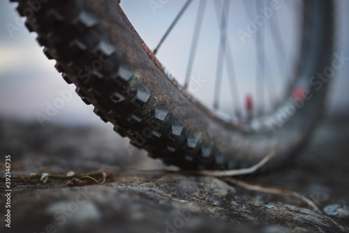 Detail of a mountain bike tire with a slightly muddy sidewall standing on a rocky surface. photo