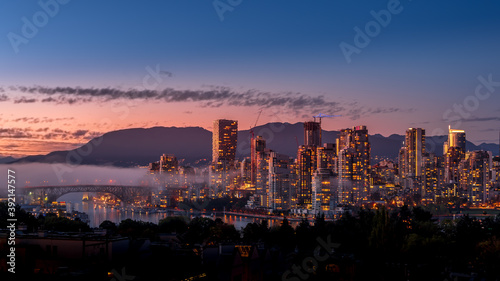 Fog drifting over the Granville Bridge as the Sun sets over the Skyline of Downtown Vancouver, British Columbia, Canada. Viewed from the South Shore of Falls Creek photo