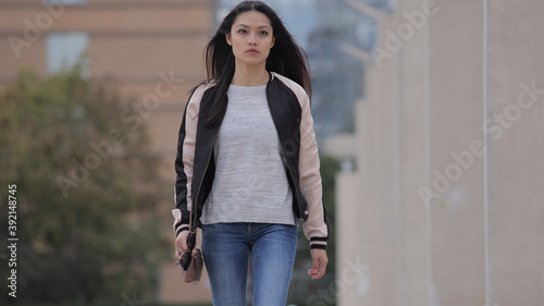 Young Asian woman walks over a square in a city - people photography
