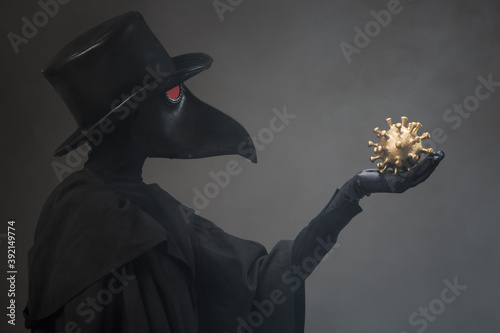 Photography The plague doctor holds a golden model of the virus in his hand.