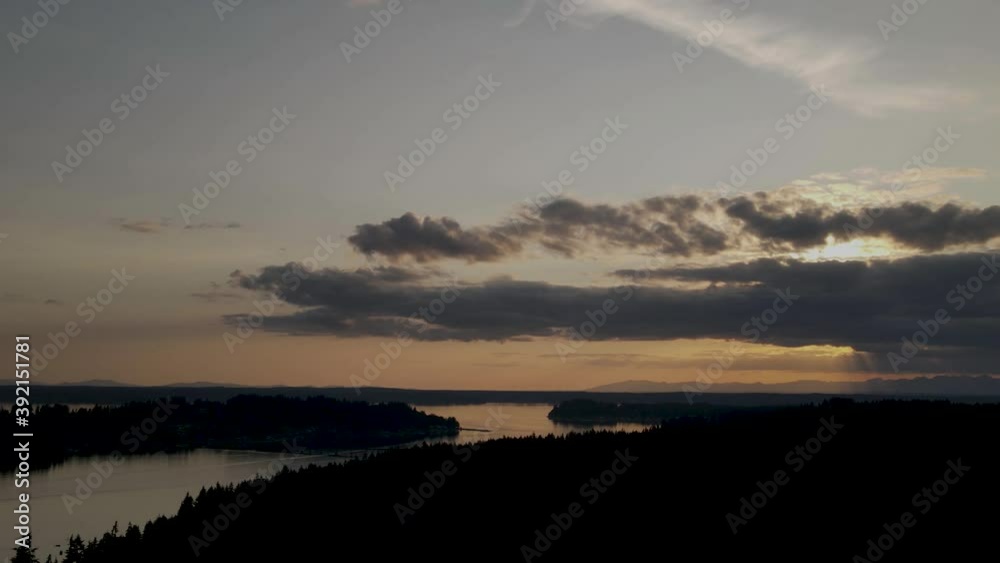 Dark clouds spread across a golden hazy sunset over Puget Sound, Washington, aerial hyperlapse Dark clouds spread across a golden hazy sunset over Puget Sound, Washington, aerial hyperlapse