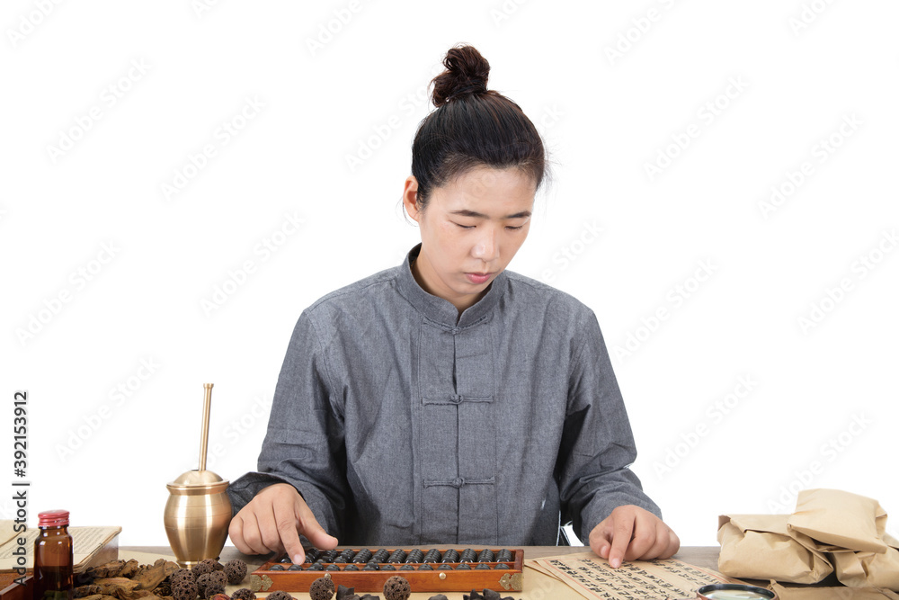 Beautiful Chinese pharmacist is using a calculator and flipping through medical books on a table full of various medicinal materials Beautiful Chinese pharmacist is using a calculator and flipping through medical books on a table full of various medicinal materials