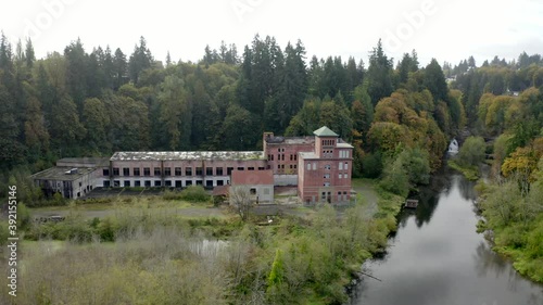 Drone flying down over river  with rustic brick building and fall colors and waterfall - Tumwater Falls Olympia WA photo