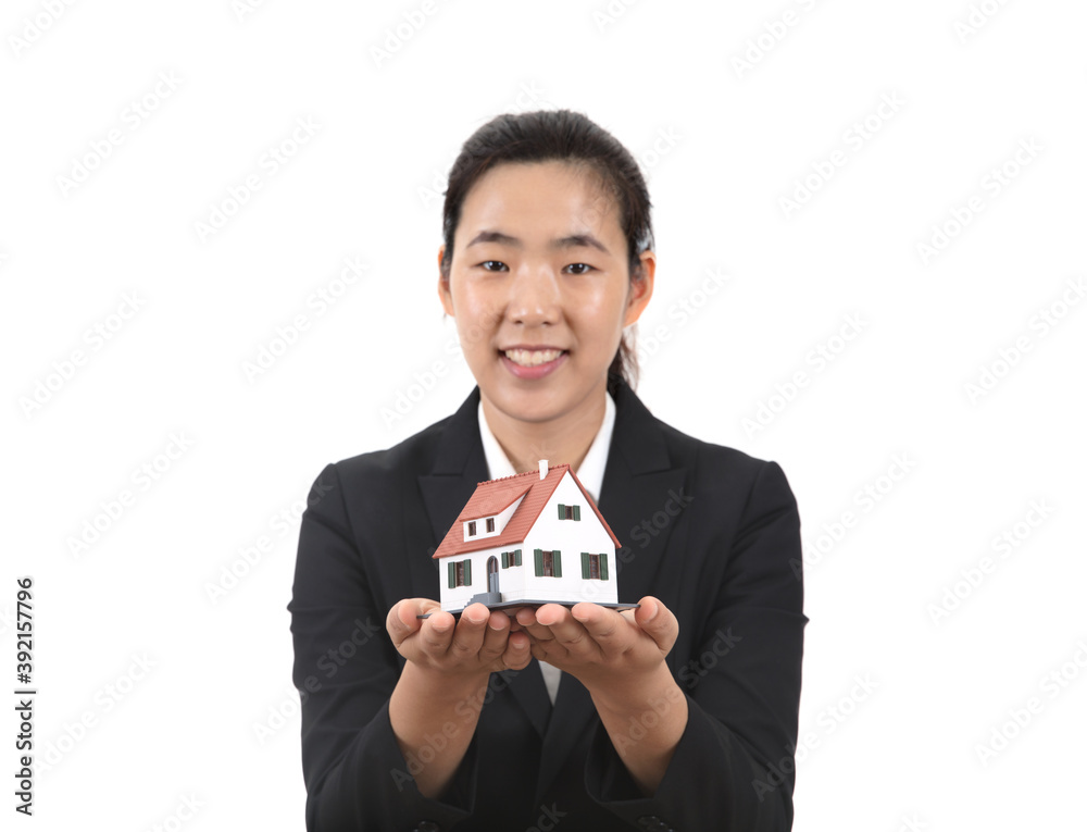 Pretty female real estate salesperson smiling in front of white background holding small house model Pretty female real estate salesperson smiling in front of white background holding small house model