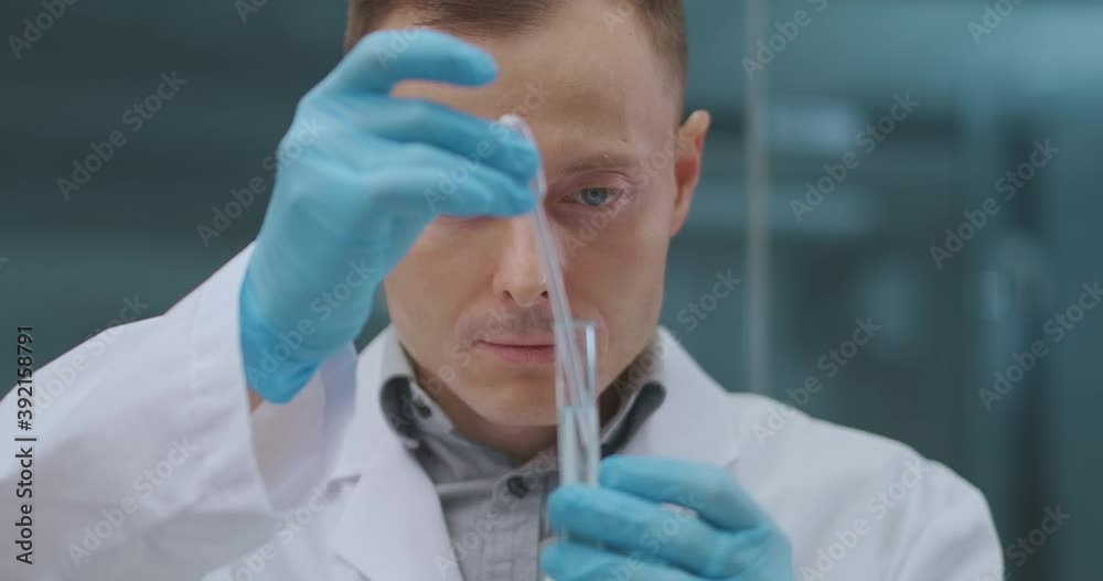 male laboratory technician is testing and analysing new drug for curing coronavirus, taking sample from test tube
