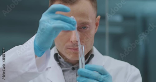 male laboratory technician is testing and analysing new drug for curing coronavirus, taking sample from test tube