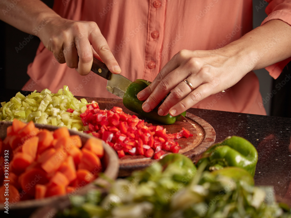 Closeup shot of a woman chopping peppers on a wooden board