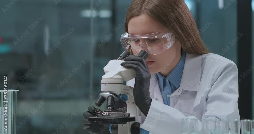 female virologist is exploring virus of covid-19 in medical laboratory, viewing it in microscope, research of coronavirus female virologist is exploring virus of covid-19 in medical laboratory, viewing it in microscope, research of coronavirus