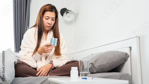 Sick Asian holding a glass of water and taking medicines from headache, Healthcare uses medicine concepts.