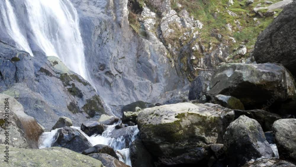 Rocky cascading waterfall flowing into jagged river rocks and boulders left slow dolly Rocky cascading waterfall flowing into jagged river rocks and boulders left slow dolly