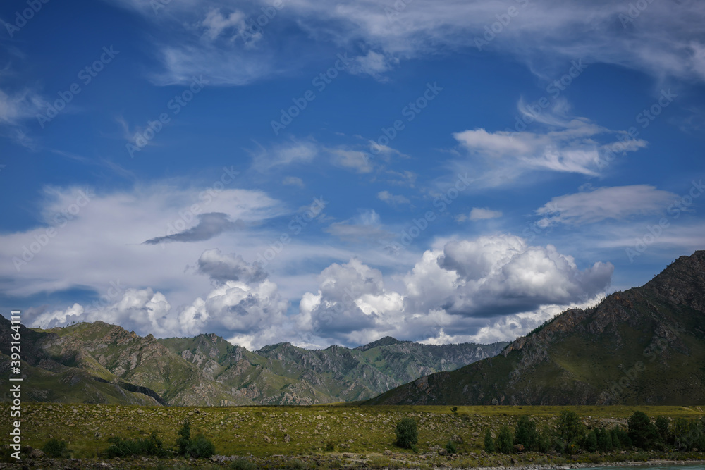 Mountain range against blue sky with white clouds. Beautiful landscape on summer day. Majestic rocks in the sunlight. Natural backgrounds.