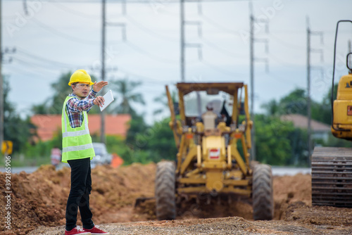 Fototapeta Asian engineers watch road rebuilding and inspect the construction of the road at the construction site