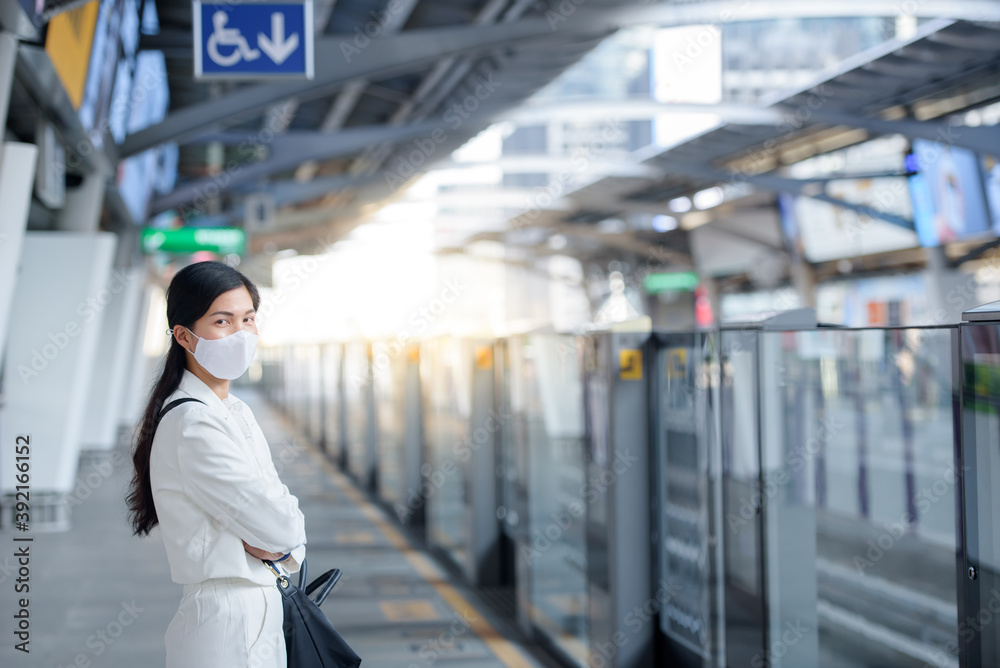 Fototapeta premium A young Asian woman wearing a mask against the novel coronavirus (Covid-19) walks in a crowd at a public train station.