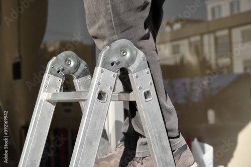 Folding ladder with a person on it. Folding ladder details. Aluminum folding ladder. 