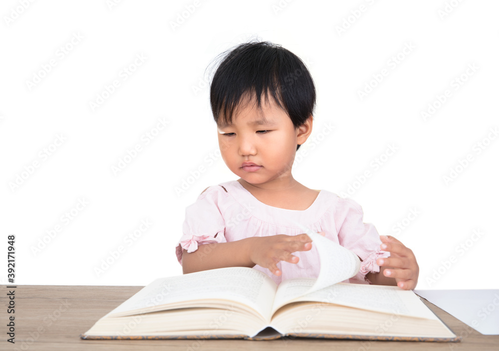 Three-year-old girl sitting at the table flipping through the books on the table Three-year-old girl sitting at the table flipping through the books on the table