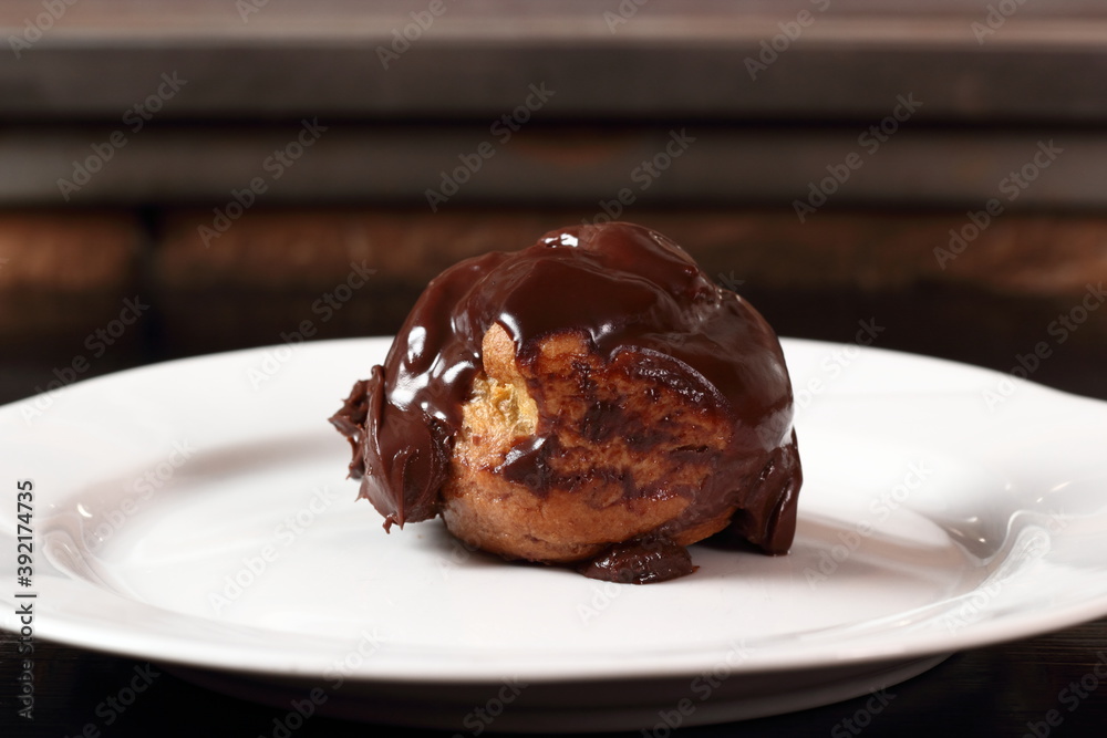 Choux pastry ball with custard filling and chocolate sauce icing
