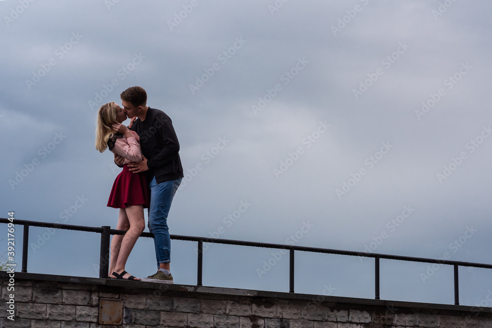 Beautiful loving each other couple is standing and kissing on on sky backgrounds