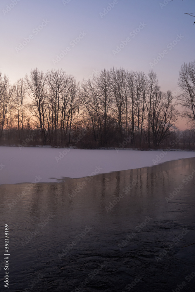 Fototapeta premium Breath of winter, first ice on the lake, dawn on a frosty morning with frost on the grass, close-up of frost, patterns on the first ice.