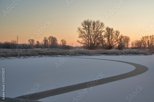 Breath of winter, first ice on the lake, dawn on a frosty morning with frost on the grass, close-up of frost, patterns on the first ice. © nikolay_alekhin
