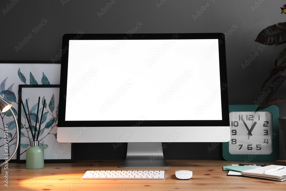 Comfortable workplace with modern computer on wooden table near black wall. Space for text Comfortable workplace with modern computer on wooden table near black wall. Space for text