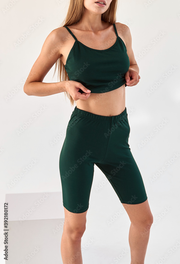 girl wears dark green leggings and dark green sleeveless top isolated. sport outfit for summer girl wears dark green leggings and dark green sleeveless top isolated. sport outfit for summer