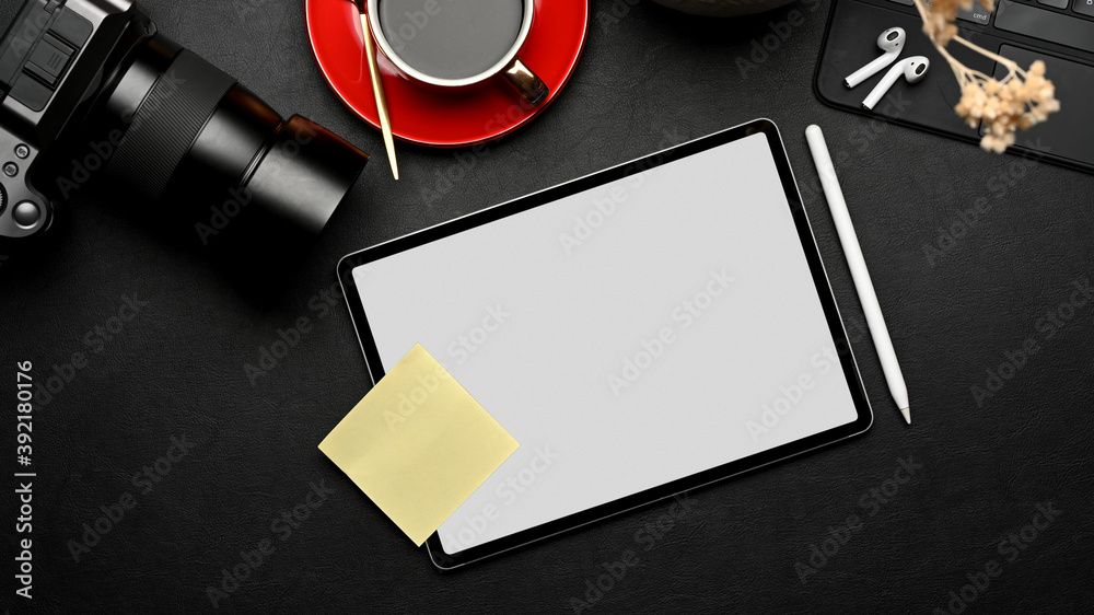 Workspace with tablet, camera, coffee cup and supplies on black table, include clipping path Workspace with tablet, camera, coffee cup and supplies on black table, include clipping path