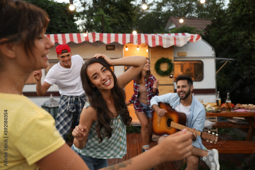 Naklejka premium Happy friends having fun near trailer. Camping season