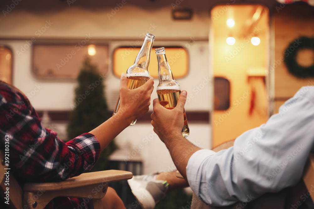 Εκτύπωση καμβά Young couple toasting with bottles of beer near trailer, closeup