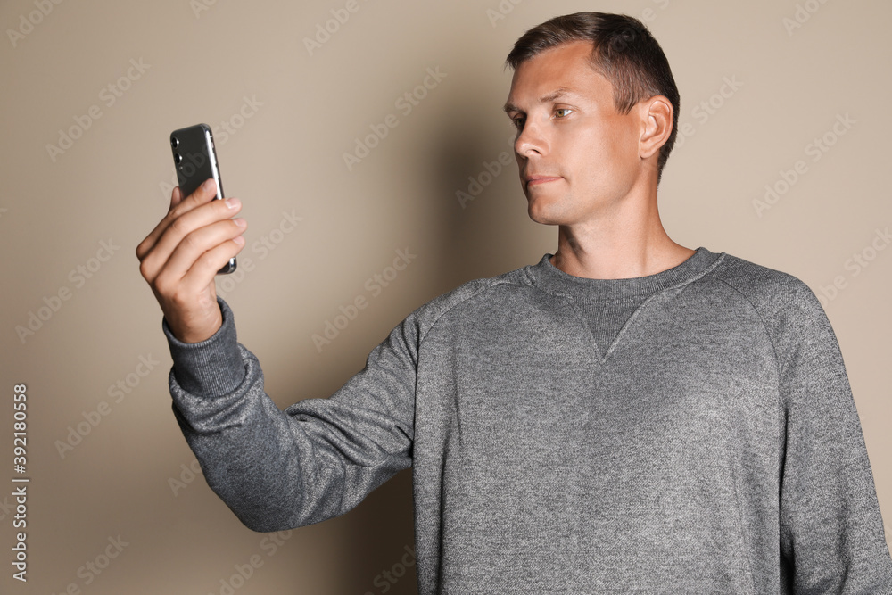 Man unlocking smartphone with facial scanner on beige background. Biometric verification Man unlocking smartphone with facial scanner on beige background. Biometric verification