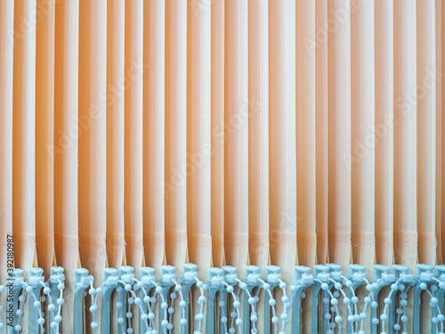 View of the vertical slats of peach-colored blinds. Parallel stripes. Abstract background.