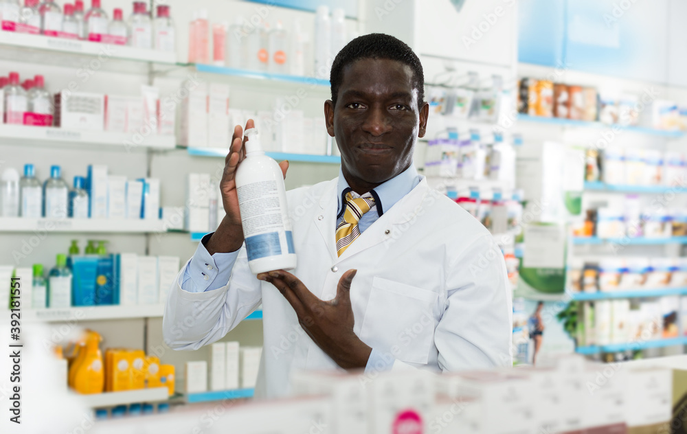 Confident African American male pharmacist showing cosmetics in pharmacy