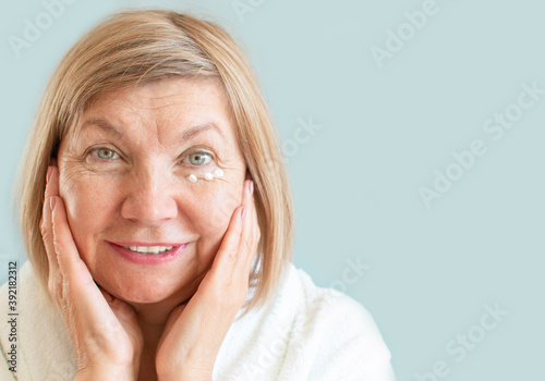 Portrait of a cheerful mature cheerful woman seniora with anti-aging cream. Natural spa treatments at home, body care concept, organic cosmetics. Anti aging concept, ealthcare and cosmetology, pension
